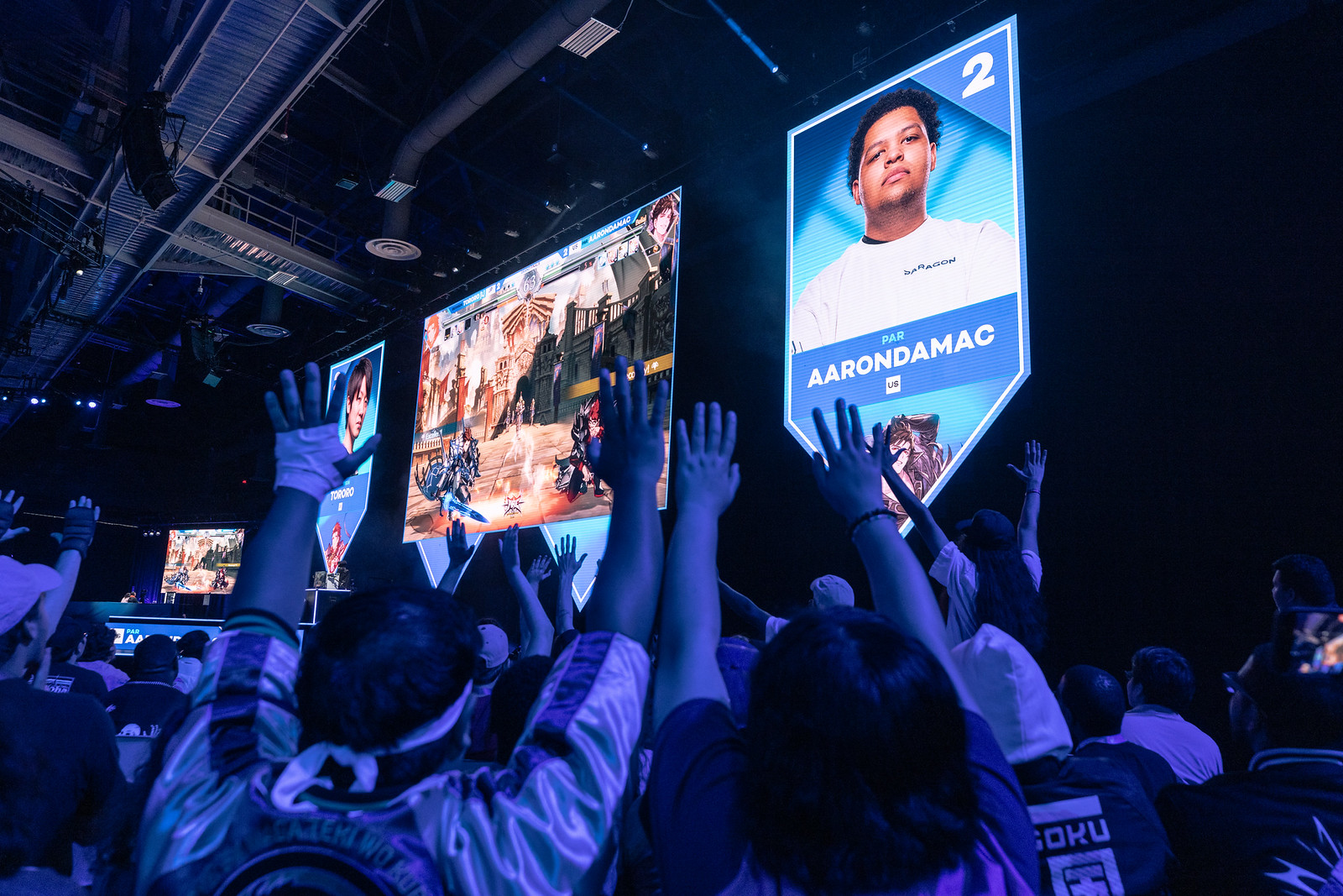 Audience raises hands watching a match on screen.