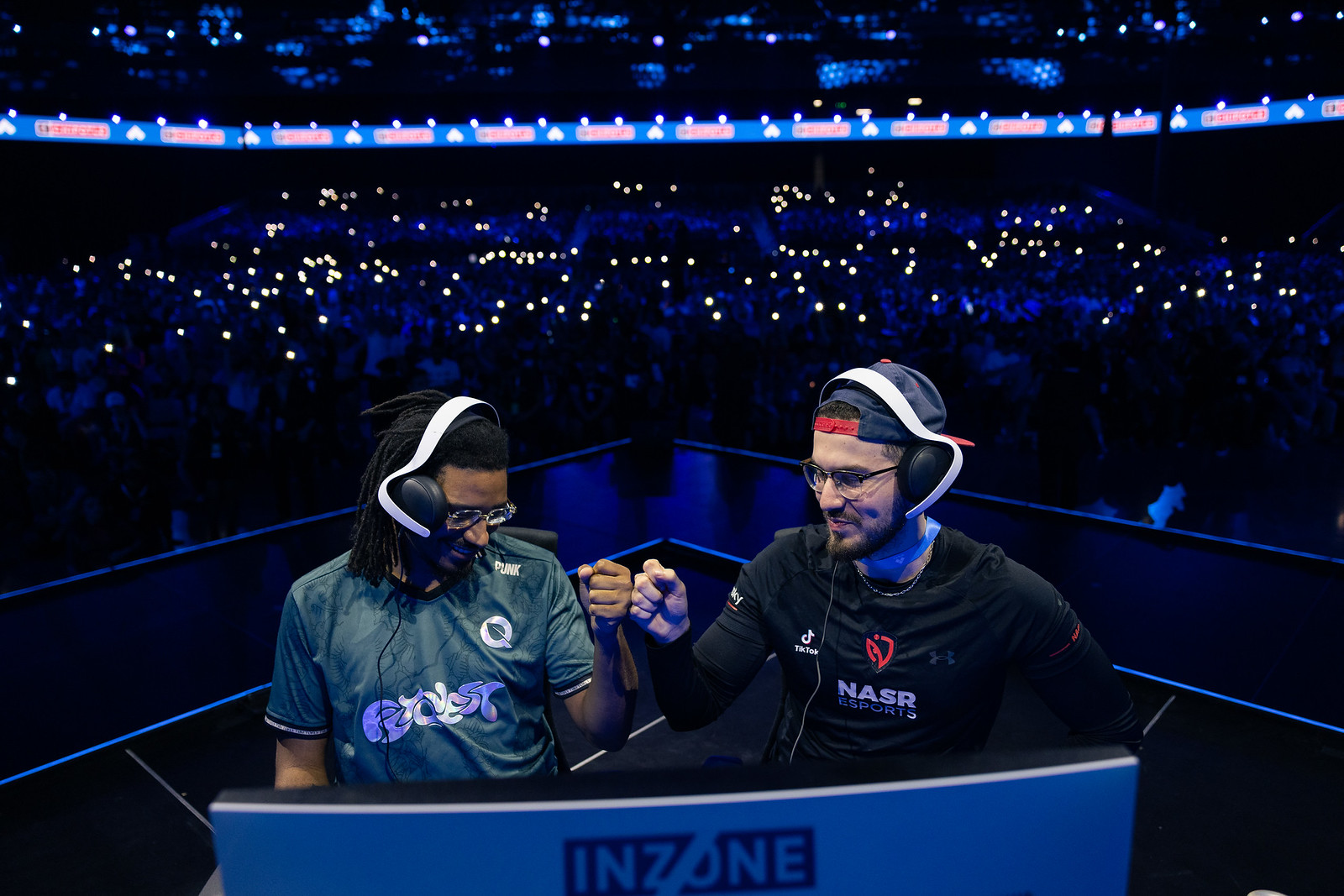 Two players fist bump on stage at a gaming event.